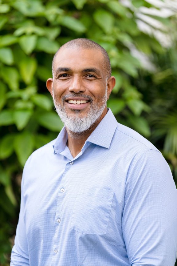 Greg Miller Headshot Smiling in front of greenery
