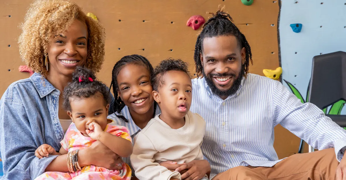 Black family of 5 two adults, one male one female and three children smiling