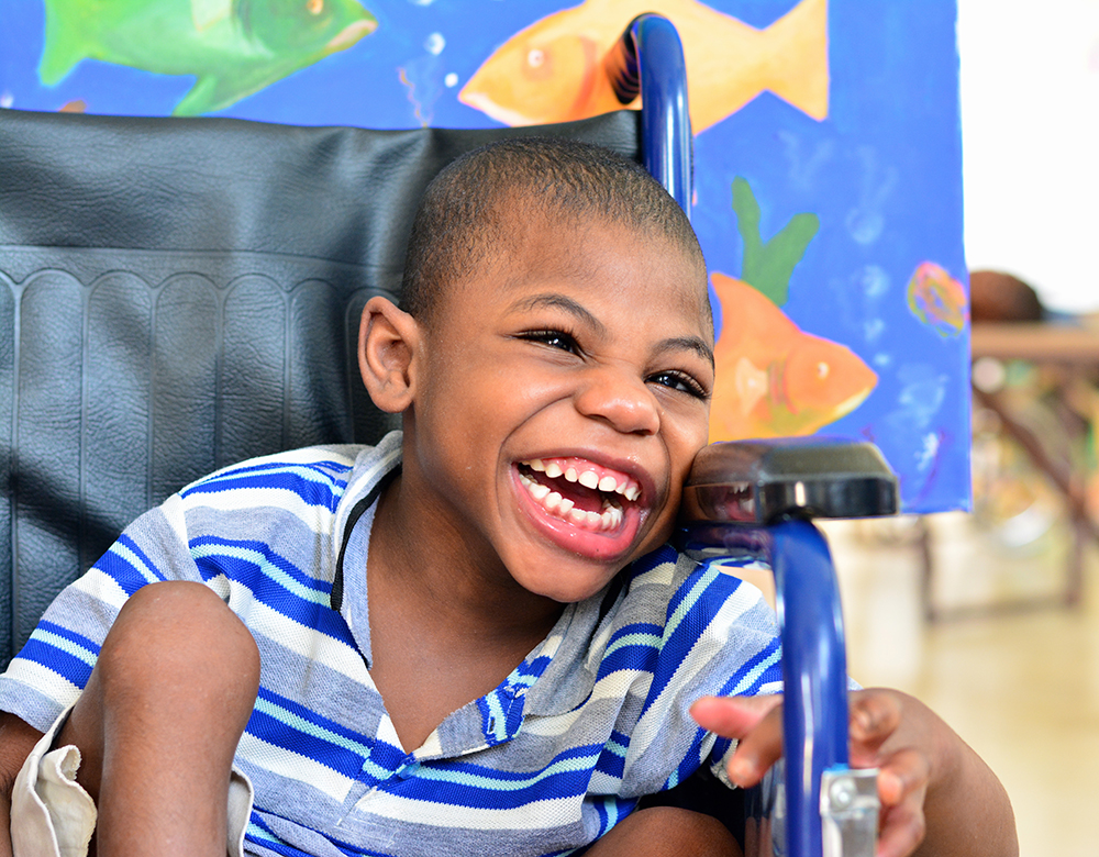 Young boy child in wheelchair smiling heartily