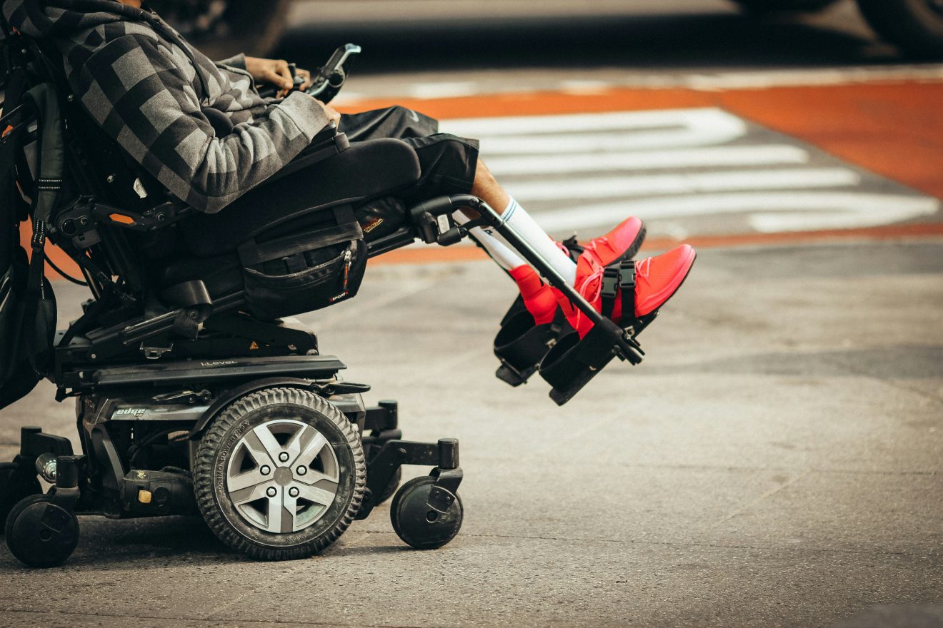 Picture of man in wheelchair being pushed across road